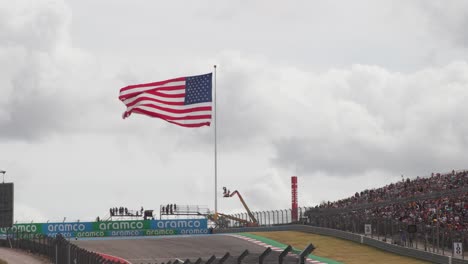 American-Flag-waving-in-the-wind-during-the-National-Anthem-at-F1-Formula-One-race-with-crowd-at-Circuit-of-the-Americas