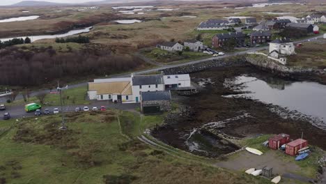 Downward-tilting-drone-shot-featuring-the-Taigh-Chearsabhagh-Museum-and-Arts-Centre-in-the-village-of-Lochmaddy-on-the-Isle-of-North-Uist,-part-of-the-Outer-Hebrides-of-Scotland