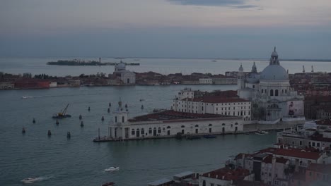 A-panoramic-view-of-the-island-of-Venice-at-sunset,-with-boats-sailing-through-its-canals