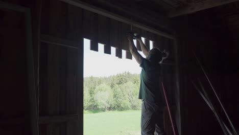 Carpenter-Cutting-Wooden-Plank-Wall-Of-A-Barn-House-Using-Electric-Saw