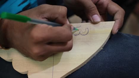 close-up-scene-in-which-a-person-is-drawing-a-drawing-on-a-piece-of-wood-and-will-cut-the-wood-using-the-drawing