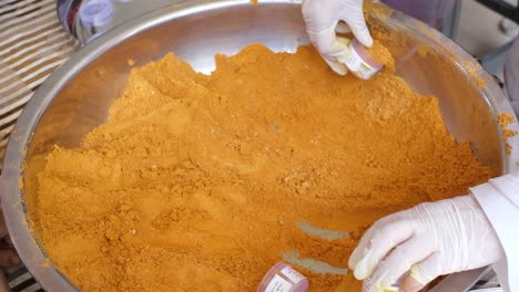 close-up-scene-in-which-turmeric-and-ginger-powder-are-filled-in-a-plastic-bottle-and-gloves-are-worn-on-both-hands-for-safety