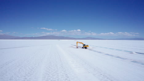 Excavator-at-huge-white-salt-flats-in-Argentina,-aerial-pull-out
