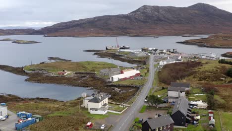 Wide-angle-drone-shot-of-Lochmaddy-and-the-surrounding-mountains,-moorland,-peatland,-sea-lochs-and-residential-buildings