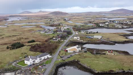 Drone-shot-of-the-landscape-around-Lochmaddy-on-the-island-of-North-Uist,-featuring-the-moorland-and-peatland,-the-distant-mountains,-lochs-and-residential-buildings