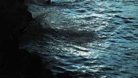 Moody-waves-crashing-into-dark-rocks-at-sunset-in-slow-motion-moody