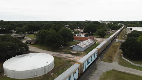 Luftaufnahme,-Die-Rückwärts-über-Einen-Güterzug-Fährt,-Der-Durch-Die-Stadt-Von-Texas-Fährt