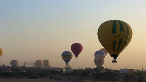 Fly-over-Luxor,-Valley-of-the-Kings-in-Egypt-in-a-Hot-Air-balloon-at-sunrise-overlooking-historical-sites