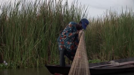 Nigerianischer-Fischer,-Der-Das-Netz-Auf-Seiner-Piroge-Hochzieht