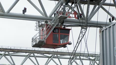 Red-crane-operator-cab-at-Europort-harbour-moving-around,-telephoto-shot