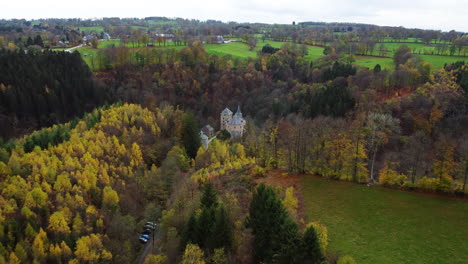 Mysterious-castle-hidden-in-deep-forest-valley,-aerial-drone-view