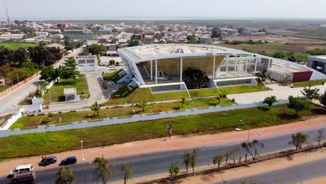 Aerial-pan-shot-of-modern-Banjul-National-Assembly-and-Banjul-City-entrance-arch-visible-in-distance-in-Gambia-on-a-sunny-day