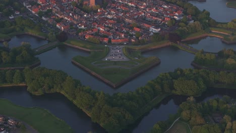 Reveal-shot-of-medieval-city-Naarden-Netherlands-vesting-during-sunset,-aerial