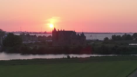 Drone-view-of-castle-Muiderslot-with-amazing-sunset-in-de-background,-aerial