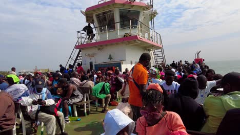 Toma-Panorámica-De-La-Multitud-De-Personas-En-Un-Ferry-En-La-Terminal-De-Ferry-De-Banjul-Autoridad-Portuaria-De-Gambia-África-Occidental-En-Un-Día-Soleado