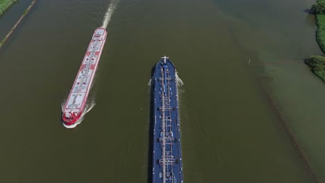 Top-shot-of-two-container-ships-passing-each-other-while-crossing-the-river-in-the-town-of-Zwijndrecht,-South-Holland,-Netherlands