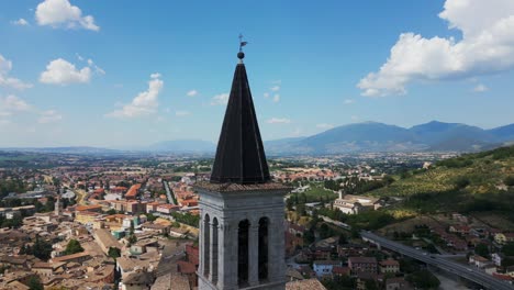 Aerial-circling-around-top-of-Spoleto-Santa-Maria-Assunta-Cathedral-bell-tower-in-Umbria-region,-Italy