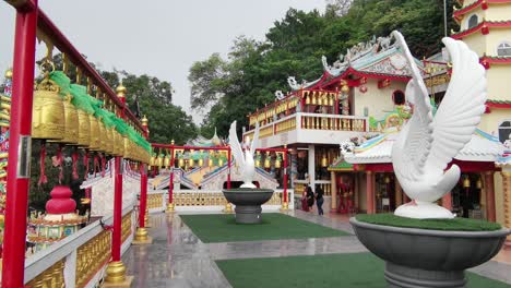 Thai-Chinese-Temple-with-Golden-Bells-and-White-Large-Birds-with-Surrounding-Buildings