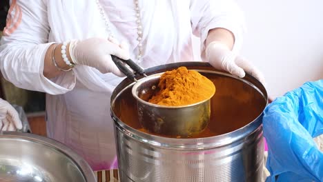 close-up-scene-in-which-a-woman-is-packing-turmeric-powder-in-a-separate-vessel