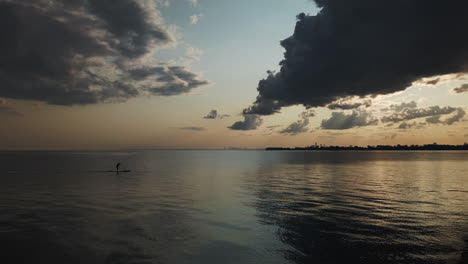 Lone-paddle-boarder-skimming-across-Lake-Ontario-under-a-beautiful-sunset-sky