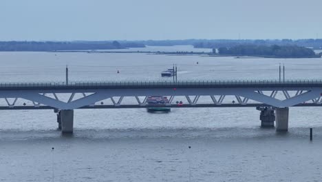 the-Moerdijk-bridges-in-Netherlands-with-cars-moving-and-a-ferry-in-passing-underneath