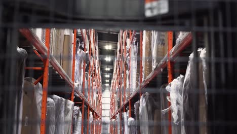 A-global-supply-chain-logistics-forklift-picker-lift-truck-drives-slowly-down-the-isle-of-a-racked-furniture-retail-distribution-center-warehouse-with-product-inventory-on-both-sides