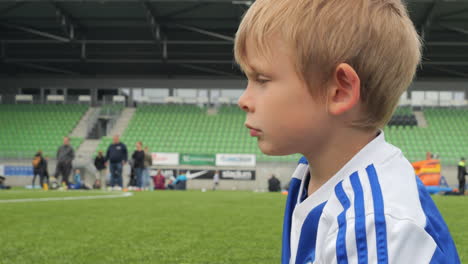 Boy-dreaming-of-football-career-sitting-on-lawn-during-match