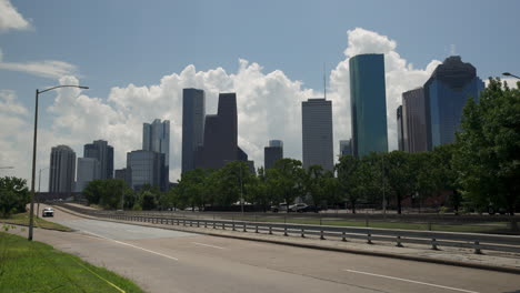 Houston,-Texas-Road-with-Downtown-Buildings-Looming-Large-in-Silhouette-in-Background