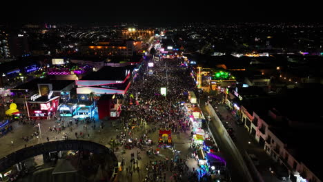 Drohne-Schoss-Rückwärts-über-Menschenmassen-Auf-Der-Messe-San-Marcos,-Nachts-In-Aguascalientes,-Mexiko