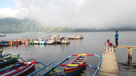 Colorful-Boats-Float-at-Lake-Beratan-Bali-Indonesia-Misty-Cloudy-Skyline-Travel-Destination,-Duck-Shaped-Canoes