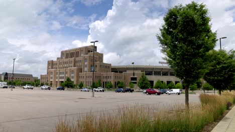 Notre-Dame-football-stadium-in-South-Bend,-Indiana-with-gimbal-video-wide-shot-walking-forward-by-trees