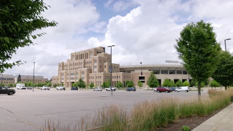 Notre-Dame-football-stadium-in-South-Bend,-Indiana-with-gimbal-video-wide-shot-walking-forward-by-two-trees