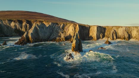 The-White-Cliffs-of-Ashleam-lighting-up-during-sunset-while-waves-are-the-breaking-on-the-rocks
