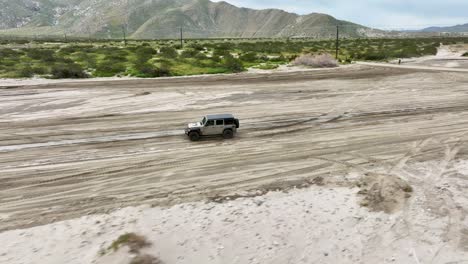 Jeep-running-on-mud-in-the-desert-of-CA-palm-springs-with-mountains-in-the-back