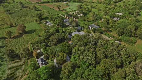 Sigiriya-Sri-Lanka-Aerial-v2-birds-eye-view-flyover-and-around-resort-hotel-surrounded-by-lush-tress,-tilt-up-reveals-beautiful-landscape-of-countryside-farmlands---Shot-with-Mavic-3-Cine---April-2023