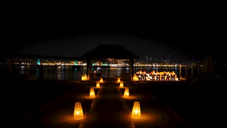 Experience-a-romantic-night-dinner-by-the-shore-for-a-couple,-with-candles-illuminating-the-pathway