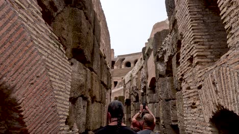 POV-Walking-With-Tour-Group-Exploring-Underground-Tunnels-At-Rome's-Colosseum-From-The-Arena-Floor