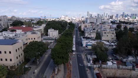 New-city-train-driving-through-suburban-area-towards-city-center-of-Tel-Aviv,-aerial-view
