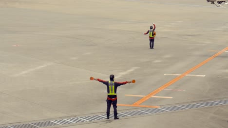 Land-airport-crew-staff-making-body-signals-to-airplane-approaching-landing-track-at-Narita-International-Airport-Okinawa-Japan-Airlines-personal-job