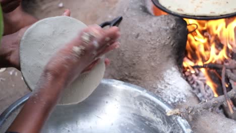 Slow-motion-scene-in-which-a-village-woman-is-kneading-millet-roti-flour-with-both-hands-on-a-trip-and-she-is-making-roti-on-the-stove,-Shot-of-an-Indian-housewife-kneading-the-wheat-dough-for-chapati