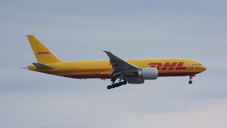 DHL-Boeing-777-cargo-plane-gliding-on-sky-with-open-landing-gears