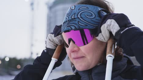 Orbiting-slow-motion-close-up-shot-of-female-skiier-taking-down-goggles