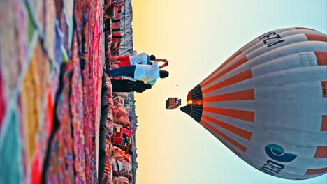 Tourists-during-sunrise-watching-hot-air-balloons-at-rooftop-terrace-in-Cappadocia,-Turkey