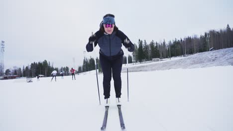 Tiro-Inclinado-En-Cámara-Lenta-Desde-Esquís-En-Movimiento-En-La-Nieve-Hasta-Revelación-De-Atleta-Femenina