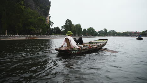 Following-a-man-rowing-with-his-feet-on-the-Li-River,-in-cloudy-Yangshuo,-China