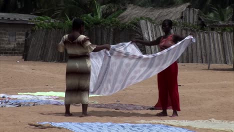 Women-folding-laundy-on-the-beach.-Nigeria