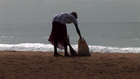 Woman-cleaning-the-beach-with-a-broom.-Nigeria