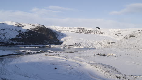 Toma-Aérea-De-Paracaidistas-Aterrizando-Dentro-De-Un-Valle-Montañoso-Congelado-En-Islandia