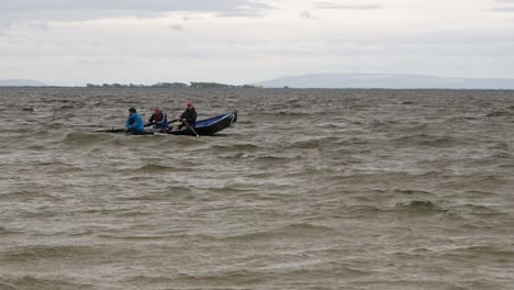 Three-man-crew-row-gently-out-to-open-ocean-in-currach-boat