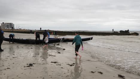 Children-play-in-shoreline-shallow-waters-as-currach-boat-racers-prepare
